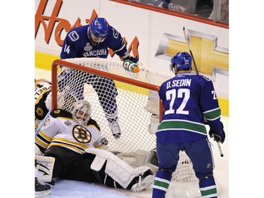 JUNE 16, 2011 --  Alexandre Burrows and Daniel Sedin of the Vancouver Canucks look on as goalie Tim Thomas of the Boston Bruins sits on the puck