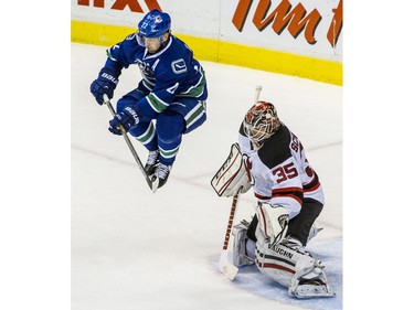 NOVEMBER 25, 2014 -- Vancouver Canucks Daniel Sedin, left leaps in front of New Jersey Devils goalie Cory Schneider, right to avoid a shot during second period NHL action in a regular season game at Rogers Arena