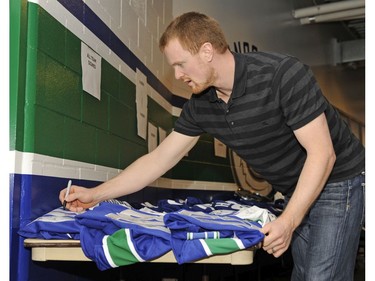 MAY 13, 2009 : Henrik autographs team jerseys before  the Vancouver Canucks clean out their locker room .