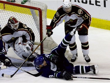Dec, 16, 2006: Henrik Sedin is knocked down by Minnesota Wild #55 Nick Schultz in front of a goal mouth scramble during the second period.