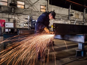 A worker uses a grinder on a steel at George Third & Son Steel Fabricators and Erectors, in Burnaby, B.C., on March 29, 2018.