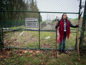 Kat Roivas, who is opposed to the expansion of the Kinder Morgan Trans Mountain pipeline, stands at an access gate at the company's property near an area where work is taking place, in Burnaby, B.C., on Monday April 9, 2018.