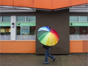 On a grey rainy day, a pedestrian carries a brightly coloured umbrella along E Hastings street, Vancouver, April 13 2018.