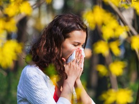 Young woman blowing her nose while being in the nature. Stock image. Getty Images/iStock Photo