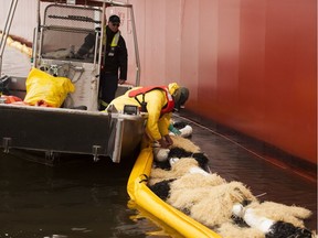 A worker puts out absorbent material around the MV Marathassa in 2015. The Crown initially planned to appeal the acquittal of the Marathassa, which discharged 2,700 litres of fuel oil into English Bay that year, but has now decided to abandoned that appeal.