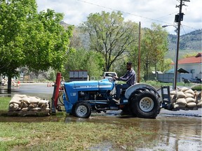 Sandeep Jhinger uses a tractor to haul sandbags to a friend's house on Harbour Key Drive in Osoyoos.