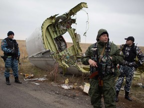 Pro-Russian gunmen stand guard as Dutch investigators (unseen) arrive near parts of the Malaysia Airlines Flight MH17 at the crash site near the Grabove village in eastern Ukraine on November 11, 2014, hoping to recover debris from the Malaysia Airlines plane.