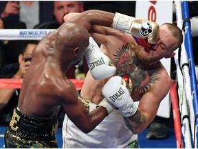 Floyd Mayweather Jr. (L) hits Conor McGregor in the sixth round of their super welterweight boxing match at T-Mobile Arena on August 26, 2017 in Las Vegas, Nevada. Mayweather won by 10th-round TKO.