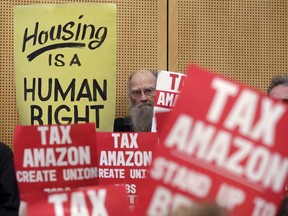 Members of the public look on at a Seattle City Council before the council voted to approve a tax on large businesses such as Amazon and Starbucks to fight homelessness, Monday, May 14, 2018, in Seattle.