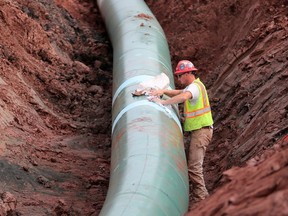 FILE - In this Aug. 21, 2017, file photo, a pipe fitter lays the finishing touches to the replacement of Enbridge Energy's Line 3 crude oil pipeline stretch in Superior, Minn.