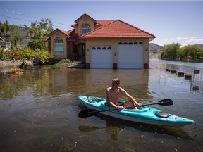 B.C. is heading into the first very warm stretch of spring, but forecasters say the heat wave due to arrive later in the week won’t be accompanied by flooding. Bryson McKinnon stops to look down a flooded street while kayaking in his neighbourhood, in Osoyoos, B.C., on Sunday, May 13, 2018.