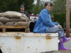 OKANAGAN FALLS, B.C. - Lynne Donesley sits on a flatbed truck loaded with sandbags "supervising" her son and grandson as they help their neighbours protect their homes near Brockie Place and 14th Avenue.