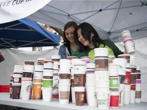 File photo: Gabby Korcheva (left) and Eliza Javier count the used coffee cups collected for a return of $0.05 cents for every cup collected at Victory Square in Vancouver, BC, October, 6, 2014.