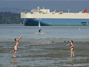 Playing it cool-- friends toss a frisbee off the waters of Spanish Banks in Vancouver.
