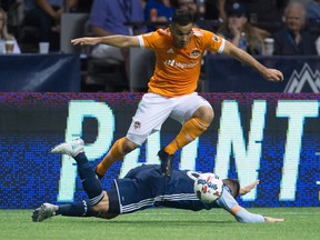 Houston Dynamo's Alex, top, leaps over Vancouver Whitecaps' Jake Nerwinski after taking the ball from him during the second half of last year's game at B.C. Place. The Whitecaps will need to get back on their feet this Friday when they host the Houston Dynamo, as they've lost four of five games.