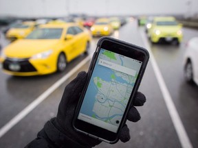 The Uber app is displayed on an iPhone as taxi drivers wait for passengers at Vancouver International Airport.