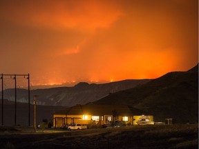 A wildfire burns on a mountain in the distance east of Cache Creek behind a house in Boston Flats last July.