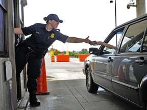 File: A U.S. Department of Homeland Security officer hands back a passport to a Canadian traveler at the Peace Arch Border Crossing.