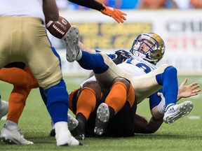 Winnipeg Blue Bombers' quarterback Alex Ross fumbles the ball while being hauled down by B.C. Lions' defender Davon Coleman during Friday's CFL pre-season game at B.C. Place in Vancouver. The Lions won 34-21.