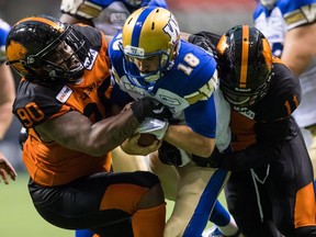 Davon Coleman, left, of the B.C. Lions assists teammate Odell Willis is stopping Winnipeg Blue Bombers' quarterback Alex Ross during CFL pre-season action in Vancouver on June 8.