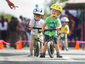 Simon, age 2, enjoys a ride on a bicycle as thousands enjoy Car Free Day on Main street in Vancouver, BC, June 17, 2018.