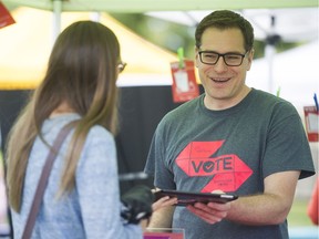 Paul Hendren, the election outreach lead at the City of Vancouver, helps sign up a voter at the Point Grey Fiesta in Vancouver on Saturday. The outreach group is working to get the vote out for the October municipal elections.