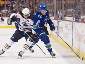 Jake Virtanen of the Vancouver Canucks battles for a loose puck with Milan Lucic of the Edmonton Oilers last season at Rogers Arena in Vancouver. The Canucks and Virtanen reached a two-year extension this week.