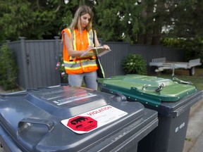 Julie Kanya, the urban wildlife coordinator for the City of Coquitlam, inspects garbage and recycling carts on the street.