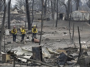 San Bernardino County Fire department firefighters assess the damage to a neighborhood in the aftermath of a wildfire, Sunday, July 29, 2018, in Keswick, Calif.