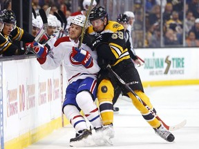 Montreal Canadiens' Andrew Shaw is checked into the boards by Boston Bruins' Tim Schaller (59).