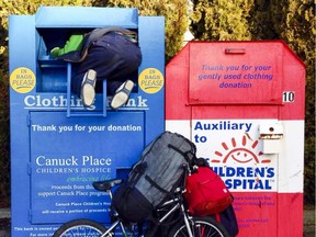 A man digs through a donation bin in Vancouver. Three people have died in B.C. in four years while trying to remove items from such bins.