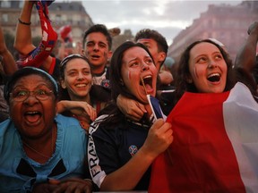 People react outside the Paris town hall after France defeated Belgium in the World Cup semifinal match between France and Belgium, Tuesday, July 10, 2018 in Paris.