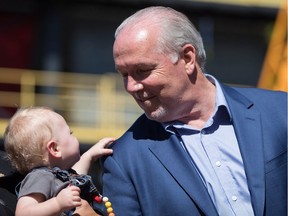 Apprentice ironworker Danielle Shaw's son Jack James, 10 months, reaches to touch B.C. Premier John Horgan while being held by Minister of Advanced Education, Skills and Training, Melanie Mark, during an announcement at the Ironworkers Training Facility at the British Columbia Institute of Technology, in Burnaby, B.C., on Monday July 16, 2018.