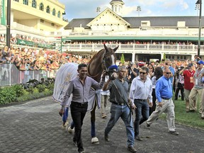 FILE - In this June 16, 2018, file photo, Triple Crown champion Justify, led by exercise rider Humberto Gomez, left, and groom Eduardo Luna, second from left, is the center of attention in the paddock at Churchill Downs in Louisville, Ky. The undefeated Triple Crown winner has been retired from racing because of fluid in his left front ankle, trainer Bob Baffert and Justify's owners announced Wednesday, July 25, 2018. They cited caution over the horse's ankle making it impossible to tell if he'd be able to race by the fall.