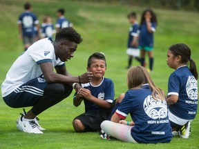 Vancouver Whitecaps midfielder Alphonso Davies, left, comforts Sakaraia Ulu, 7, after he hurt his hand during the Hope and Health event for Indigenous youth at the Musqueam First Nation, in Vancouver, on Monday July 9, 2018. Whitecaps players and coaches host soccer drills and games and children participating are given a pair of new or gently worn soccer cleats for free at the day long camp.