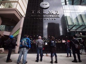 File: People look at written messages posted on the building outside the official opening of the Trump International Hotel and Tower in Vancouver, B.C., on Tuesday February 28, 2017.