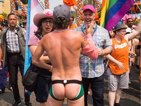 A partially-clothed reveller stops to greet British Columbia Premier John Horgan, right, as he marches in the Vancouver Pride Parade in Vancouver, B.C., on Sunday, August 6, 2017. Organizers estimated between 500,000 and 650,000 people would attend the event.