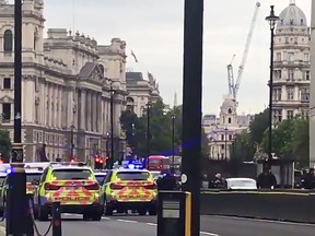 This grab taken from a video posted by Twitter user EwelinaUO shows armed police surrounding a silver car after it crashed into barriers outside the Houses of Parliament on August 14, 2018 in central London.