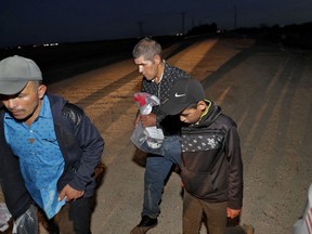 Three of four arrested Guatemalan nationals, two men and a 12-year-old boy, surrender to a U.S. Customs and Border Patrol agent, Wednesday, July 18, 2018 along the international border in Yuma, Ariz. Thousands of families and unaccompanied children are continuing to cross the U.S. border in the Yuma Sector of Arizona and California even after learning of the government's family separation policy upon apprehension.