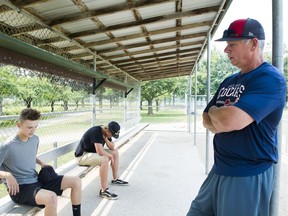 Chilliwack Cougar baseball players Carter Harbut, left, and Connor Dykstra, centre, with coach Shawn Corness sit in the Fairfield Island baseball dugout as they discuss the suspension of players after a brawl in Chilliwack on Aug. 10.