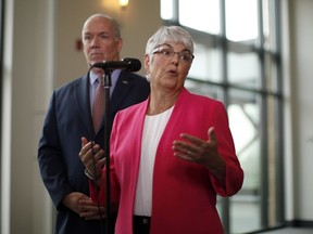 B.C. Premier John Horgan looks on as MLA Carole James answers a question during a media scrum following a meeting with federal ministers at the Vancouver Island Conference Centre during day two of the Liberal cabinet retreat in Nanaimo, B.C., on Wednesday, August 22, 2018.