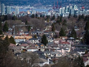 A condo building is seen under construction surrounded by houses as condo towers are seen in the distance in Vancouver on Friday, March 30, 2018.