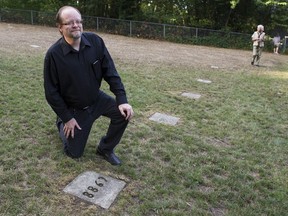 New Westminster Coun. Jaimie McEvoy kneels beside the grave marker for Gordon Hawley in the restored B.C. Penitentiary Cemetery in New Westminster Wednesday. McEvoy led the city task force that restored the cemetery in the Glenbrook Ravine Parklands.