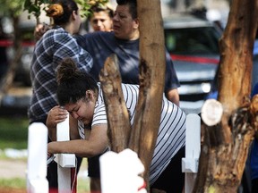 In this Sunday, Aug. 26, 2018, photo, Amber Ayala, who lost siblings in a fatal fire, hugs a wooden cross at the scene in Chicago. (Erin Hooley/Chicago Tribune via AP)