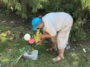 A neighbour places flowers at the scene of a crash that killed one woman and critically injured another in Central Saanich on Vancouver Island Monday evening.