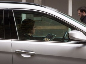 A woman uses an iPad while behind the wheel of a vehicle stopped in traffic at a red light in downtown Vancouver on Monday, October 20, 2014.