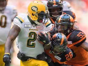 Edmonton Eskimos' C.J. Gable is tackled by B.C. Lions' Anthony Orange (No. 26) and teammate Jordan Herdman during CFL action in Vancouver on Thursday, Aug. 9.