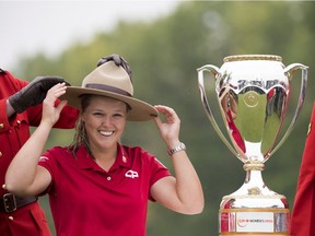 An RCMP officer put a hat on Brooke Henderson after the golfer from Smiths Falls, Ont., accepts the trophy for winning the CP Women's Open in Regina on Aug. 26.