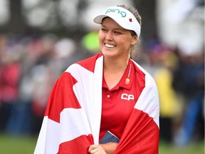 Canada's Brooke Henderson is wrapped in a Canadian flag as she celebrates her win at the CP Women's Open in Regina on Sunday.