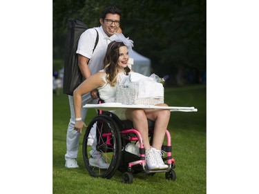 Juan Cortez pushes Jessica Kruger up the hill as she balances their table for the 7th Annual Le Dîner en Blanc at the VanDusen Botanical Garden in Vancouver on Thursday.